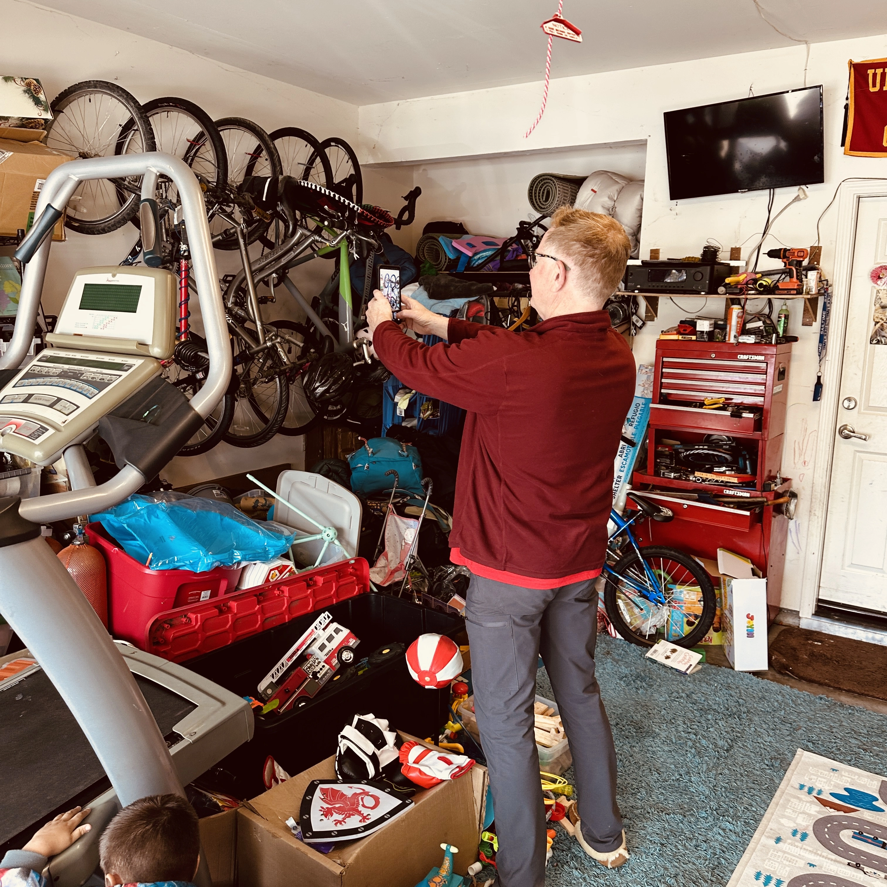 Person using phone to photograph items in a packed garage