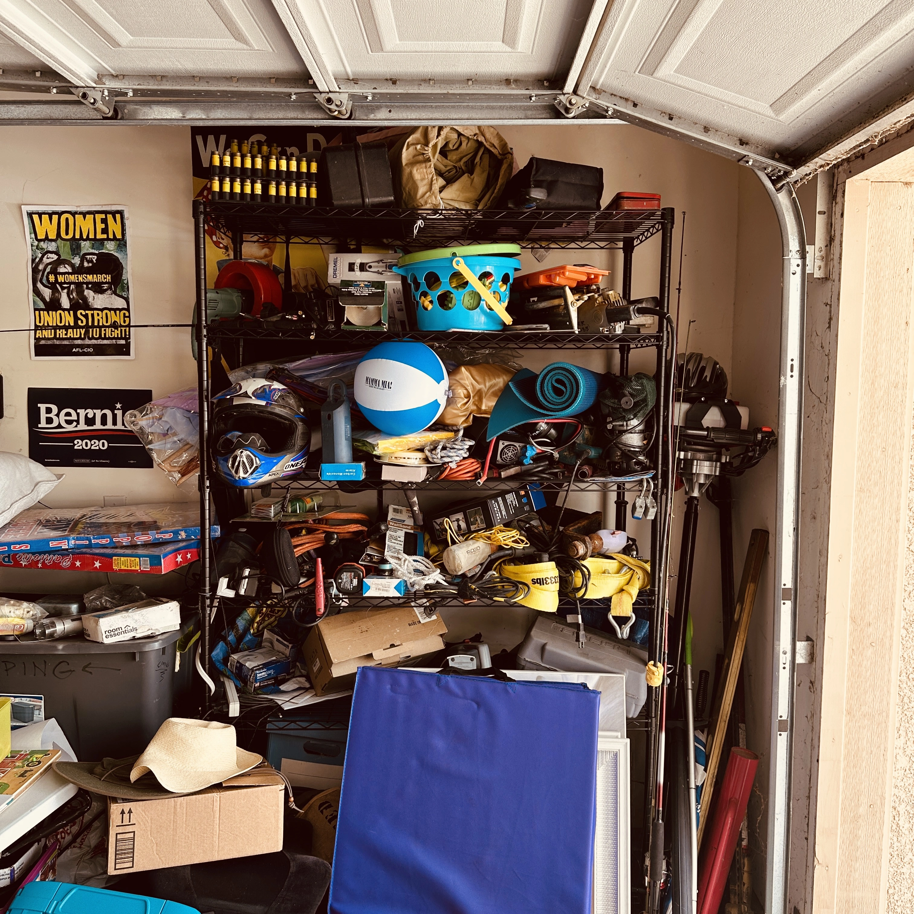 Packed garage shelving overflowing with tools, sports gear, toys, and household items